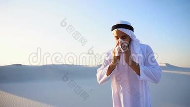 在炎热的夜晚，阿拉伯男孩站在沙质沙漠中，感到寒冷而不愉快。